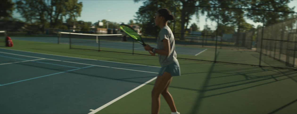 A girl is hitting the tennis ball on the court