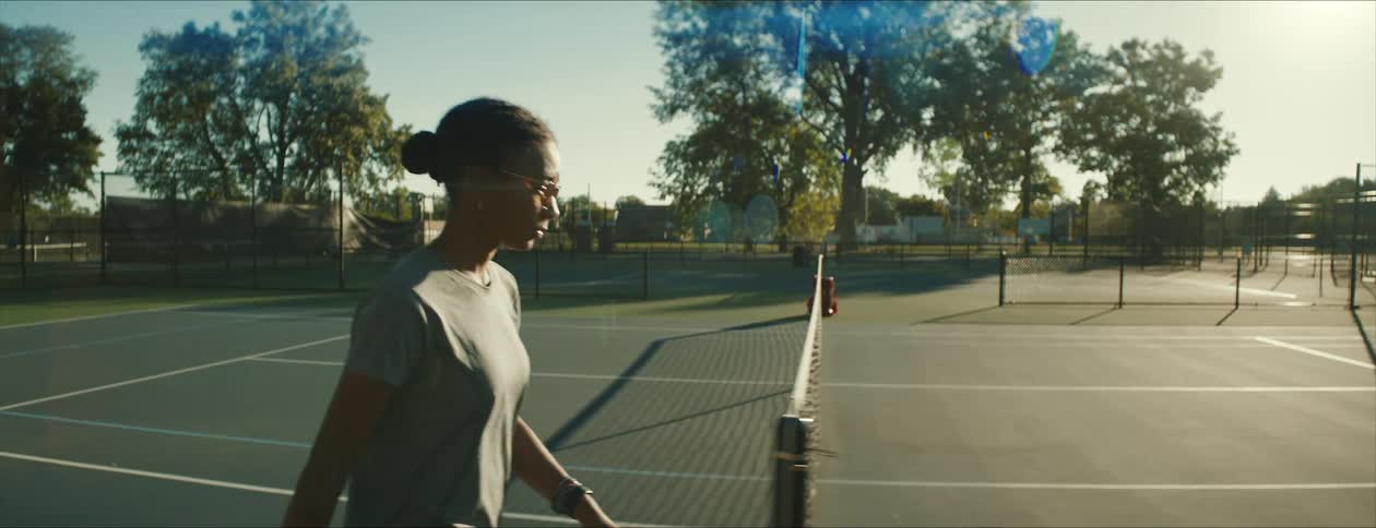 A young woman is walking on the tennis court to play some tennis