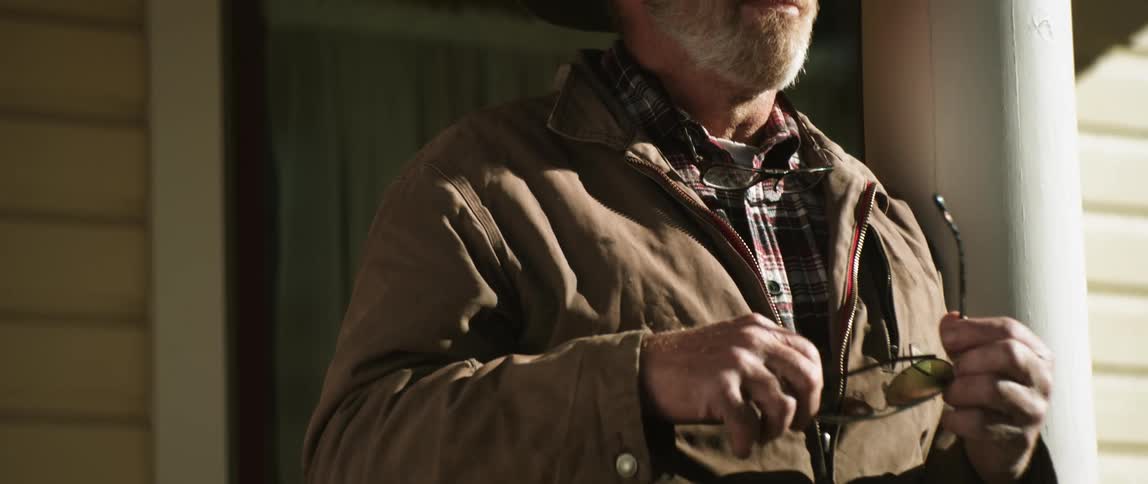 A man reaches in to his pocket and pulls out a pair of sunglasses and puts them on