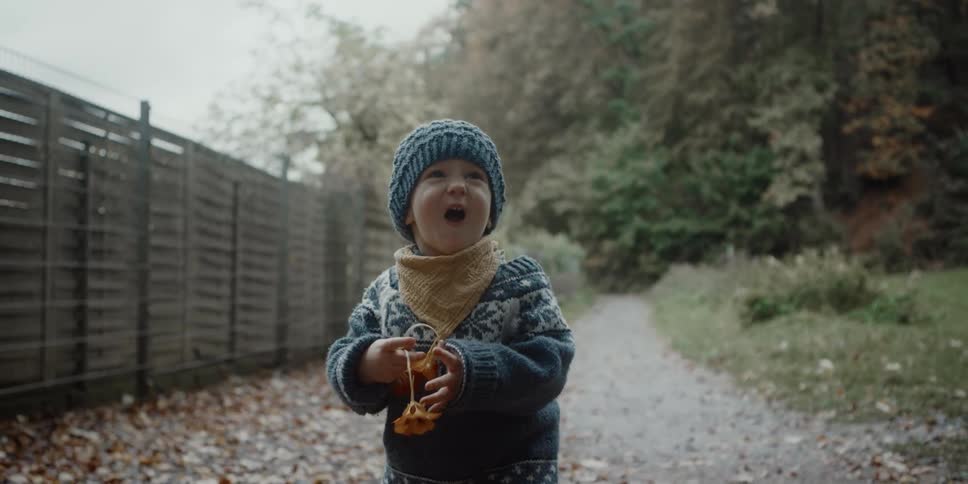 A little boy is walking down a path holding flowers