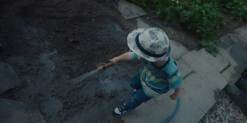 A person is watering dirt in a yard
