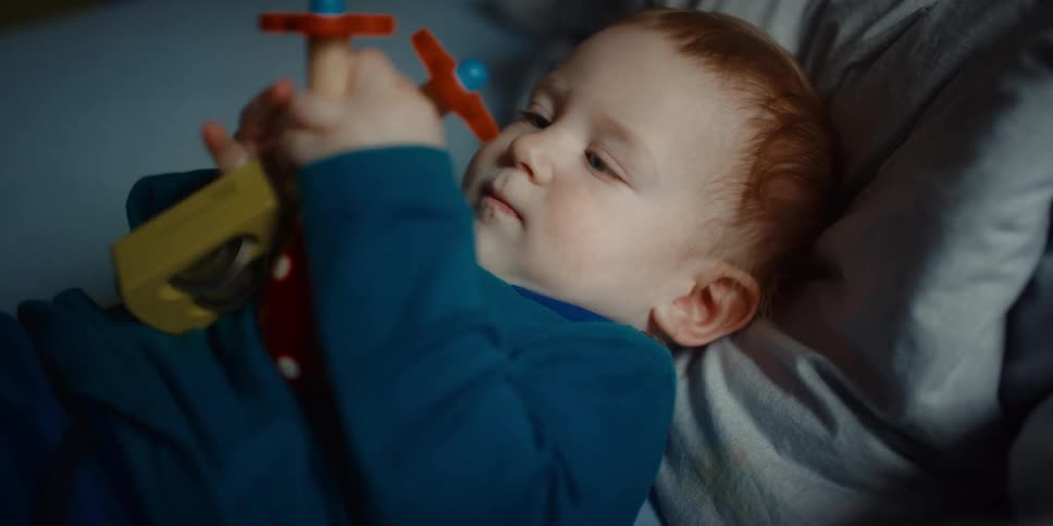 A baby is laying down playing with a toy