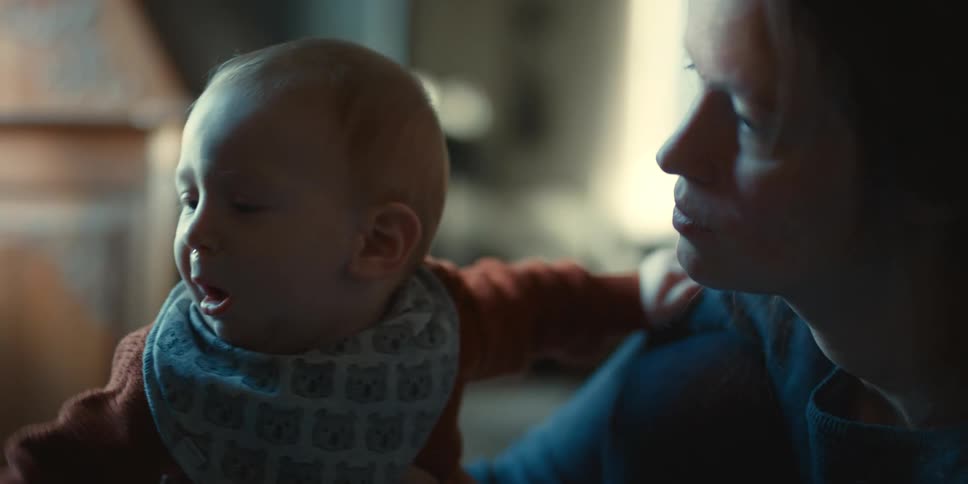 Woman cuddles baby wearing bib before the baby turns away
