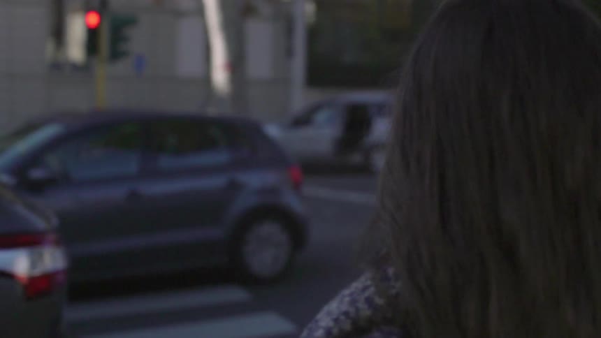Two women wait to cross a busy city street on a cold evening