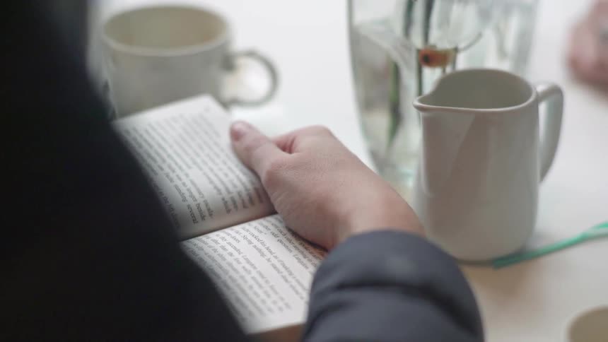 A person sitting at a table reading a book
