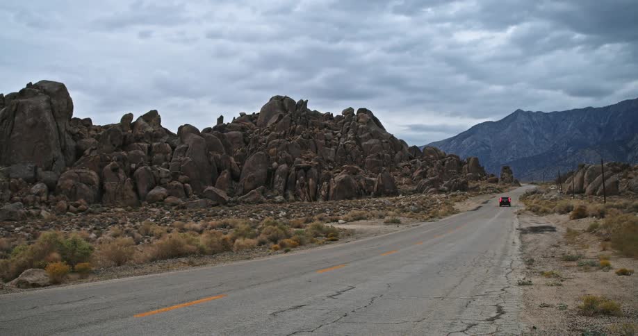 A car drives down a road past rock formations
