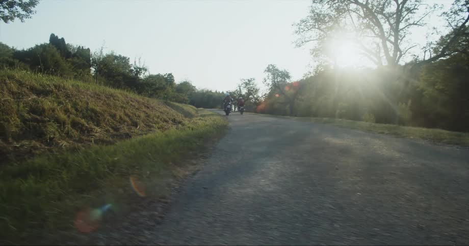 An dolly shot of two women driving fast down the road on motorcycles