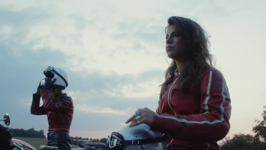 Two women are sitting on motorcycles outdoors
