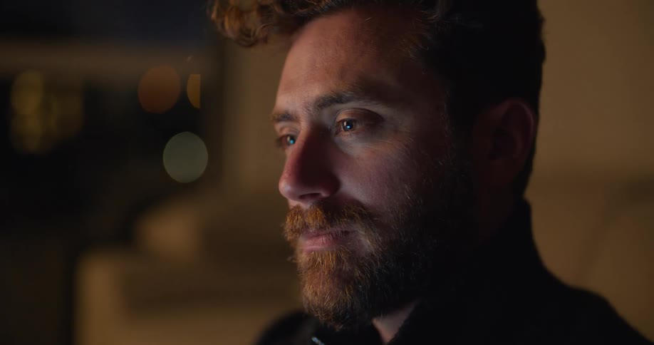 Bearded man contemplating while typing on laptop