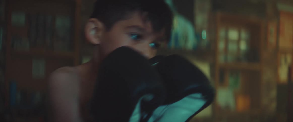 A boy strikes a punching bag in a boxing gym during the day