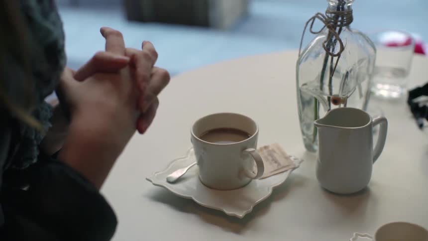 A person using their hands while talking over coffee