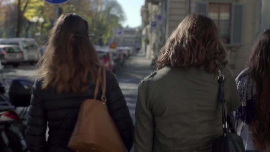 Three women walking down a sidewalk