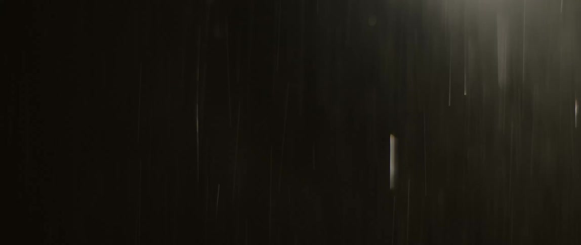 Light shines on pouring rain falling in the darkness