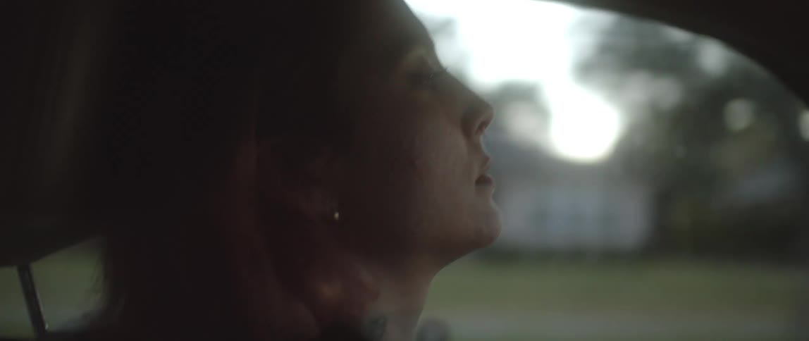 A older woman who looks sad is driving in her car