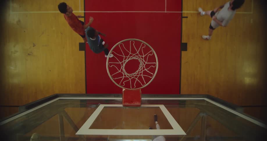 Top down view of a young man performing a slam dunk on a basketball court