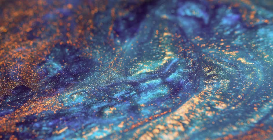 A blue liquid substance ripples and moves as stripes grow outward and a gold glitter rises to the surface