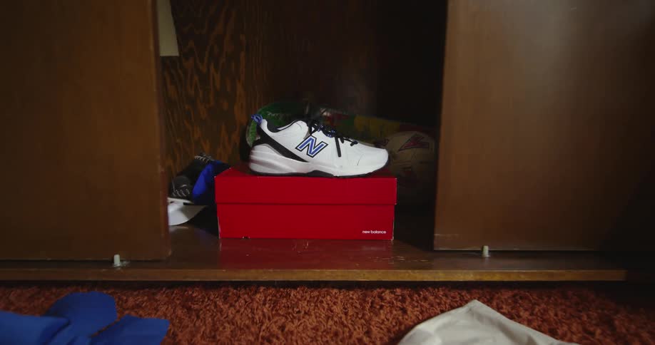 Sneaker is dropped onto shoe box near its pair then closet is closed in messy room