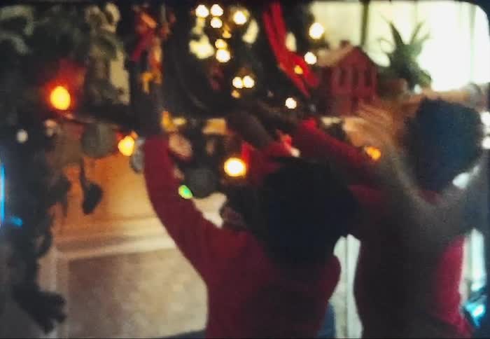 Family placing christmas decorations at home caught on vintage film