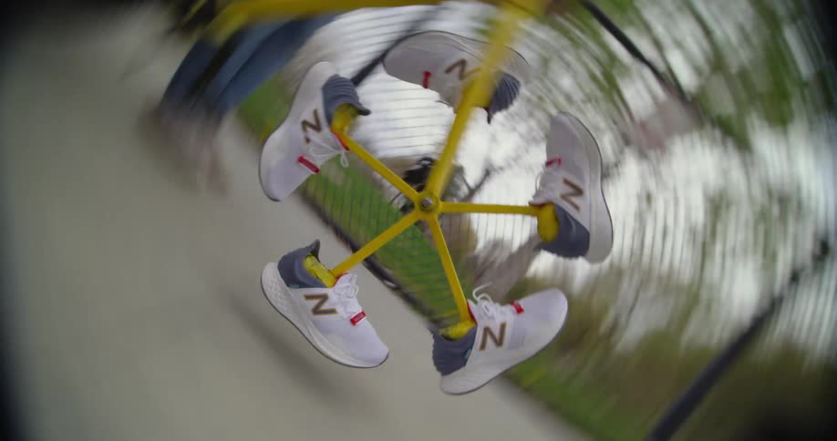 White sneakers spin on a spoke levitating in front of a fence