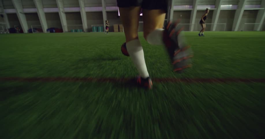 A girls soccer team practicing on an indoor grass field