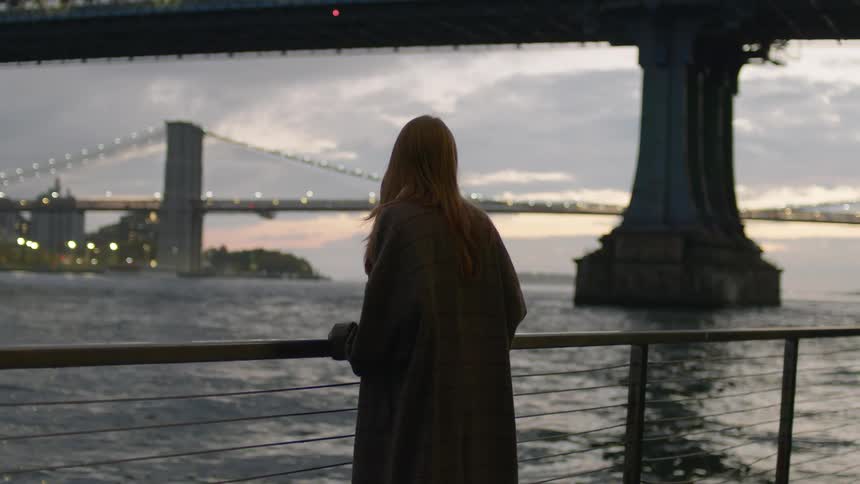 A woman is watching the sunset by the bridge