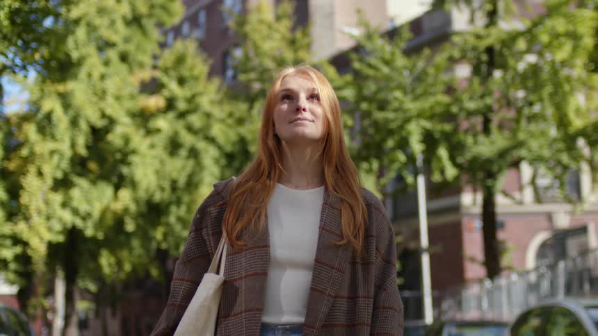 A young white woman is walking outdoors in a small town