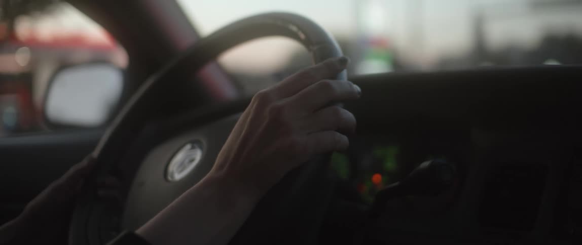 Woman taps on steering wheel in car