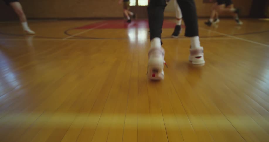 Man dribbles and attempts layup during basketball game in gym