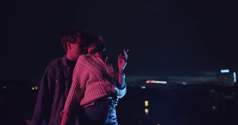 A couple smoke and drink while dancing on the rooftop of a building