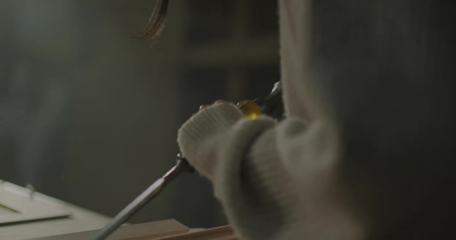 A young woman is chiseling wood