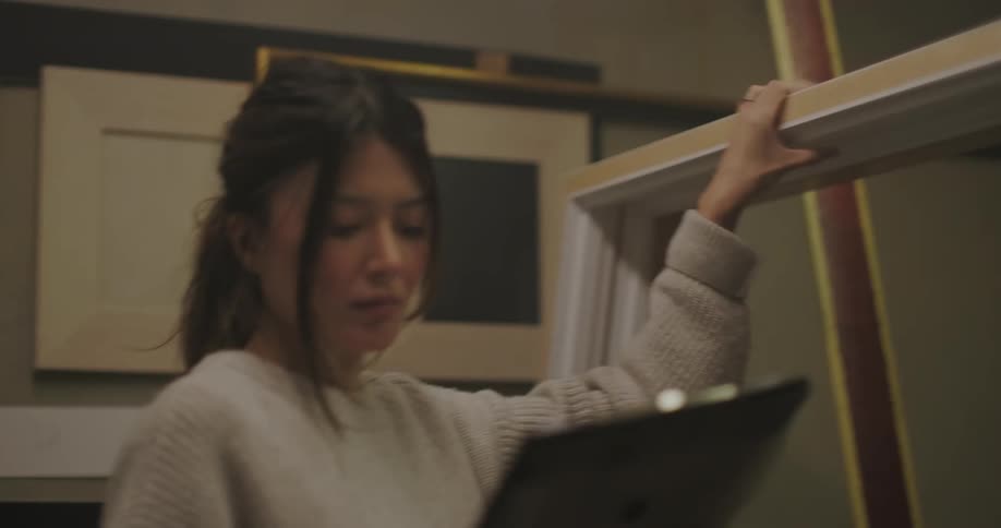 A young woman inspects picture frames