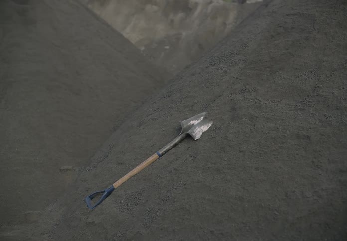 Small amounts of dirt fall down mounds toward where shovel lies