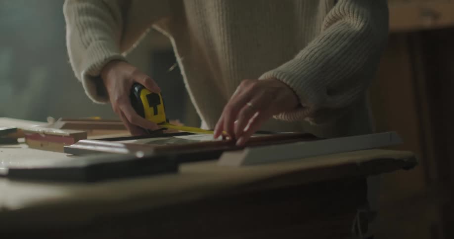 A young woman measures a picture frame