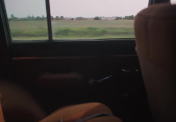 Walkie talkie and briefcase sit in backseat of vehicle driving through countryside