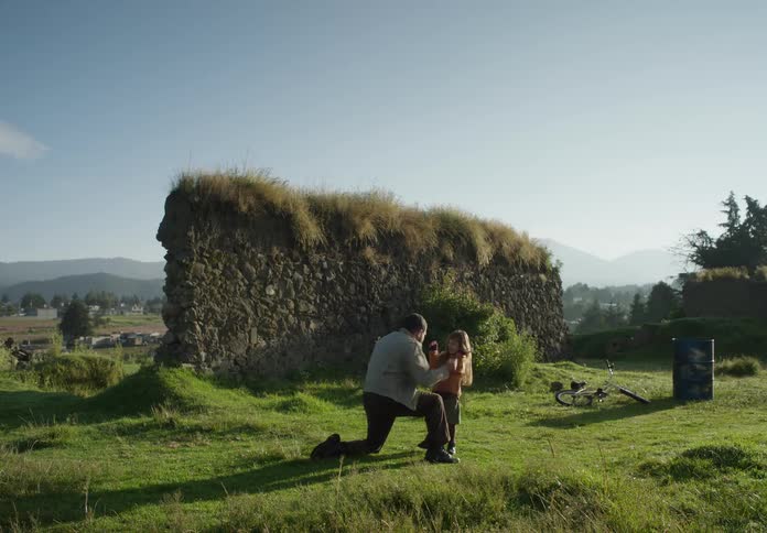 Father and daughter play with each other on green lawn near a cottage in the countryside