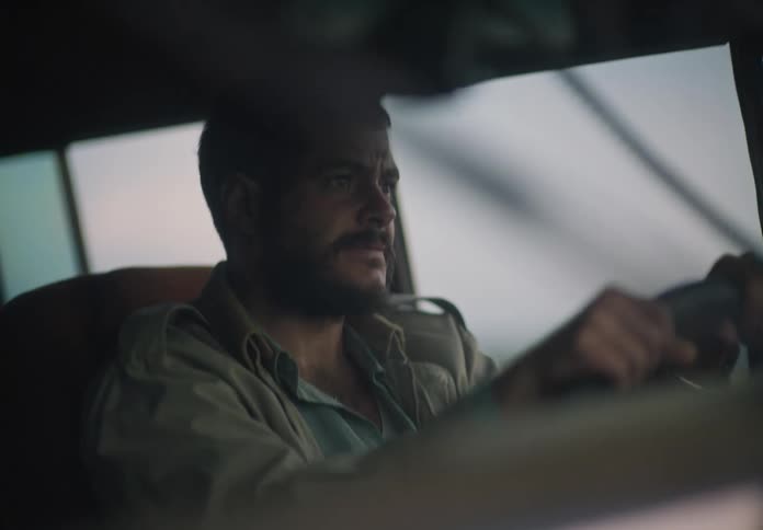 A man looks in his rearview mirror several times as he drives