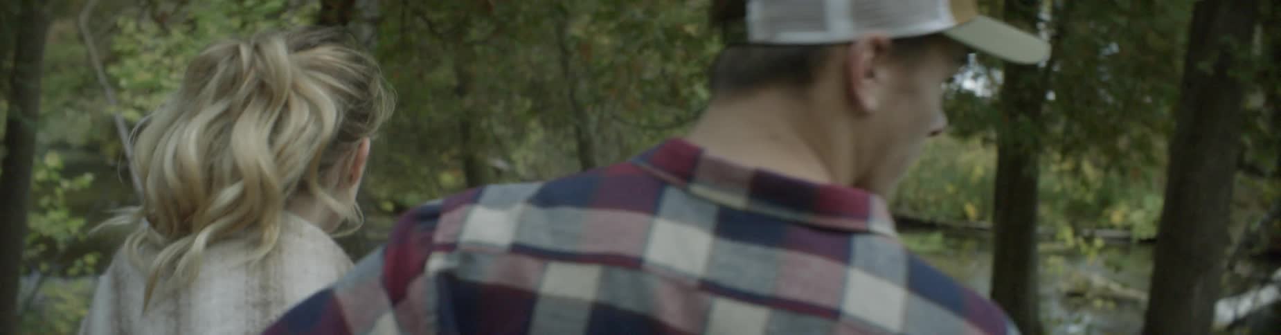 A couple walks under trees together