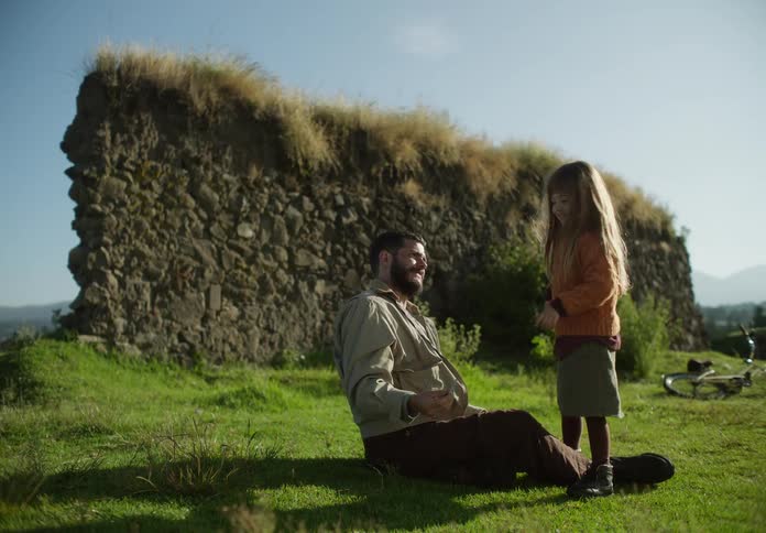 A man is playing with his daughter as he lights a firework and throws it