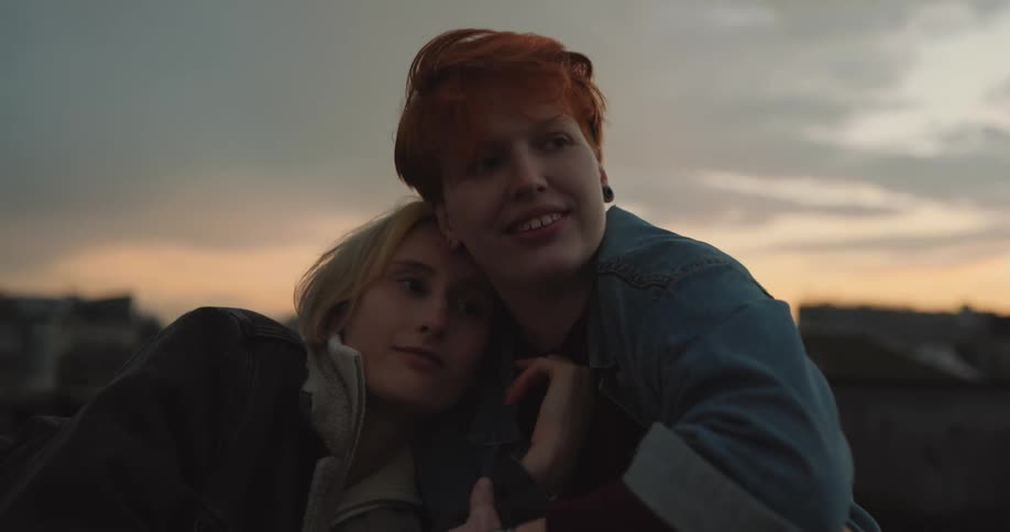 A woman rests her head on her partners shoulder while sitting outside