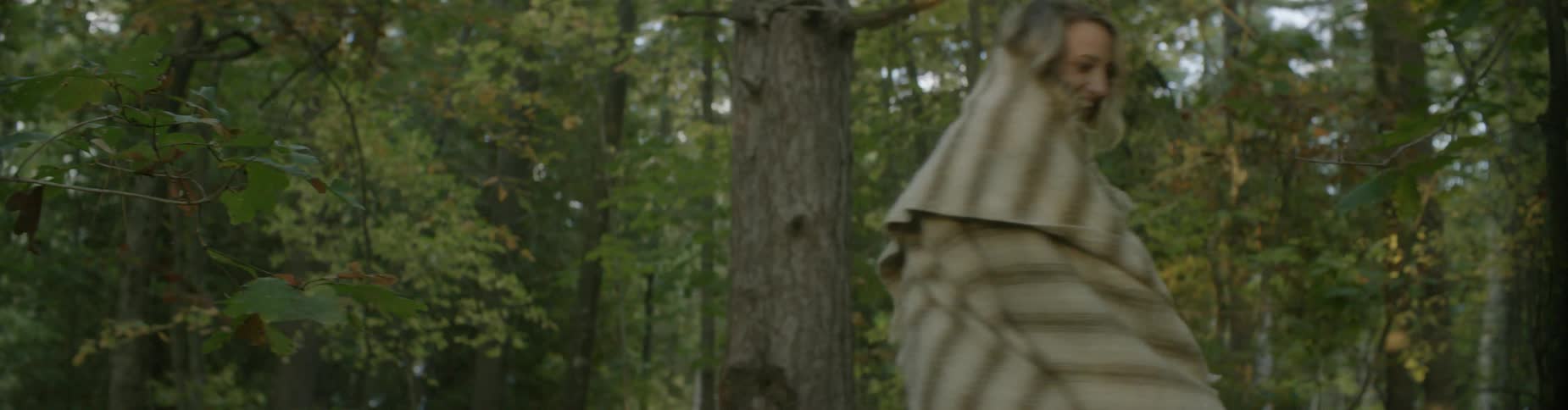 A woman wrapped in a blanket rides on a man's shoulders