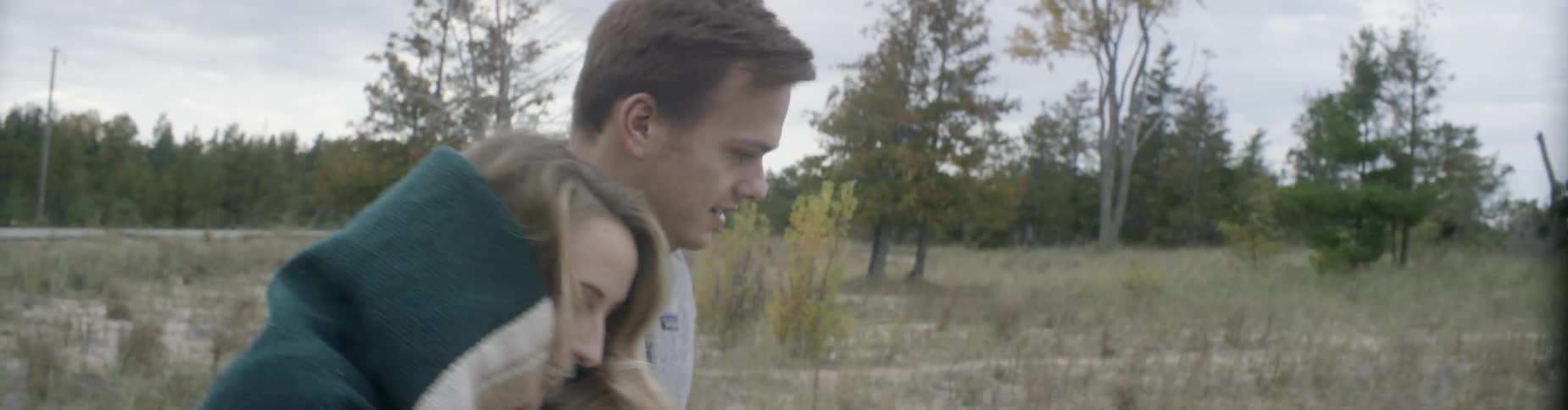 A man and woman walk over a field together