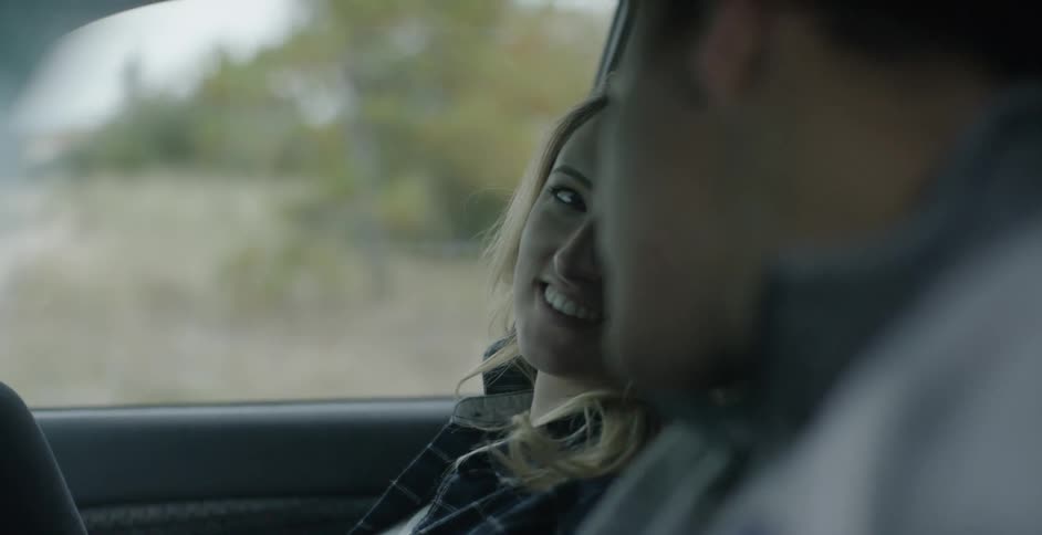 A man and woman smiling and talking as they sit in a car