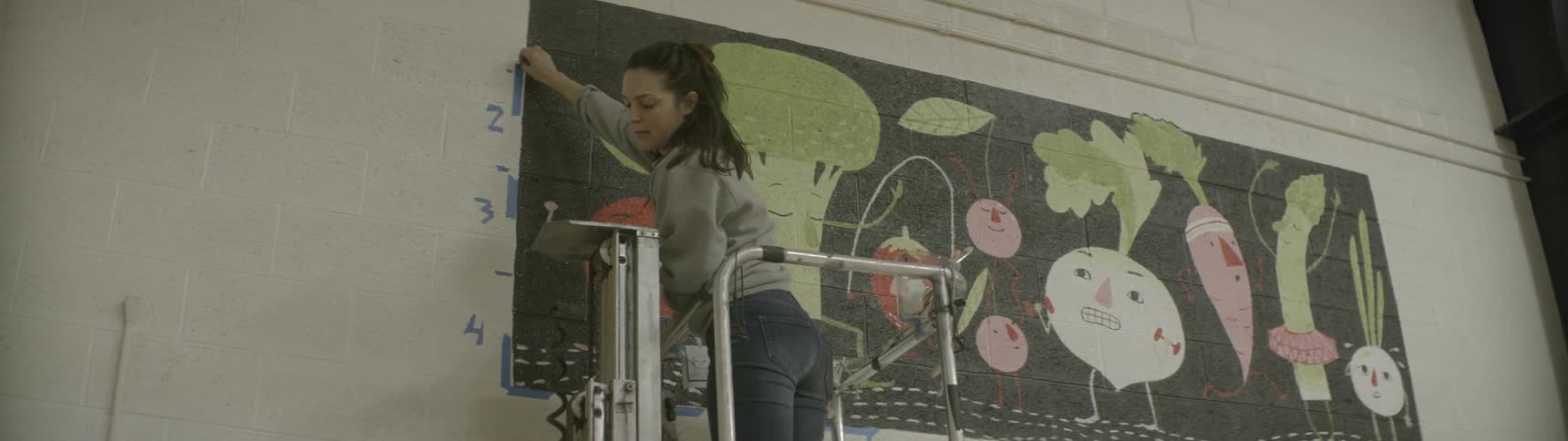 A woman is on a lift pulling tape from a wall