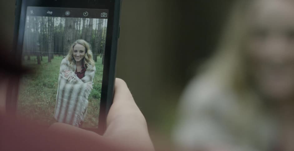 A woman is getting her photograph taken with a phone camera
