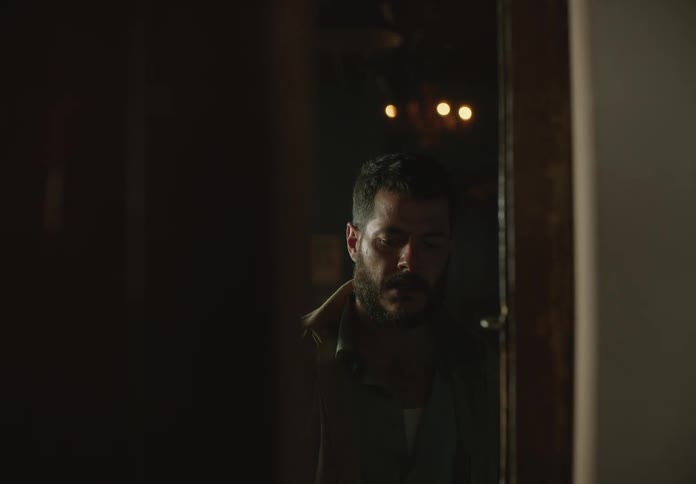 Tired man inside a house slowly approaches a door before collapsing