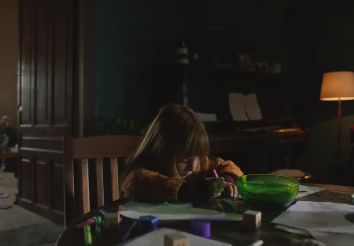 Man places bowl of water onto table and kisses girl before land shock vibrates table and she stops coloring