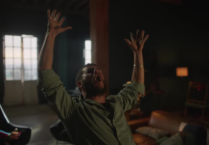 A man raises his arms up while yelling at home