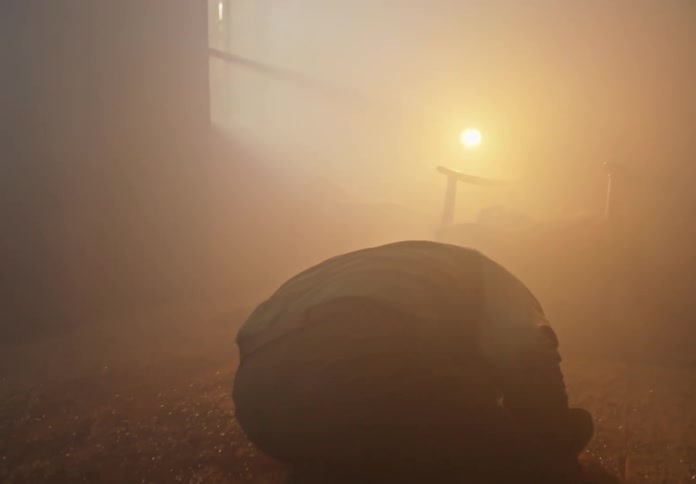A man on the ground in a smokey room that has glass on the floor