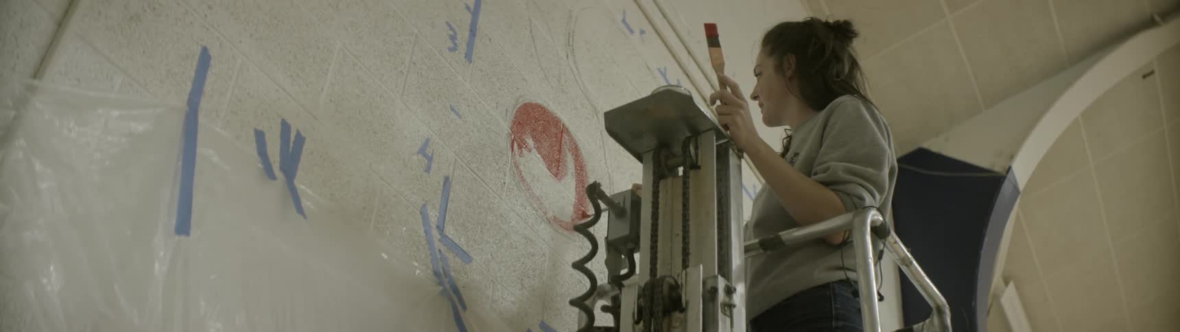A artist paints on a wall