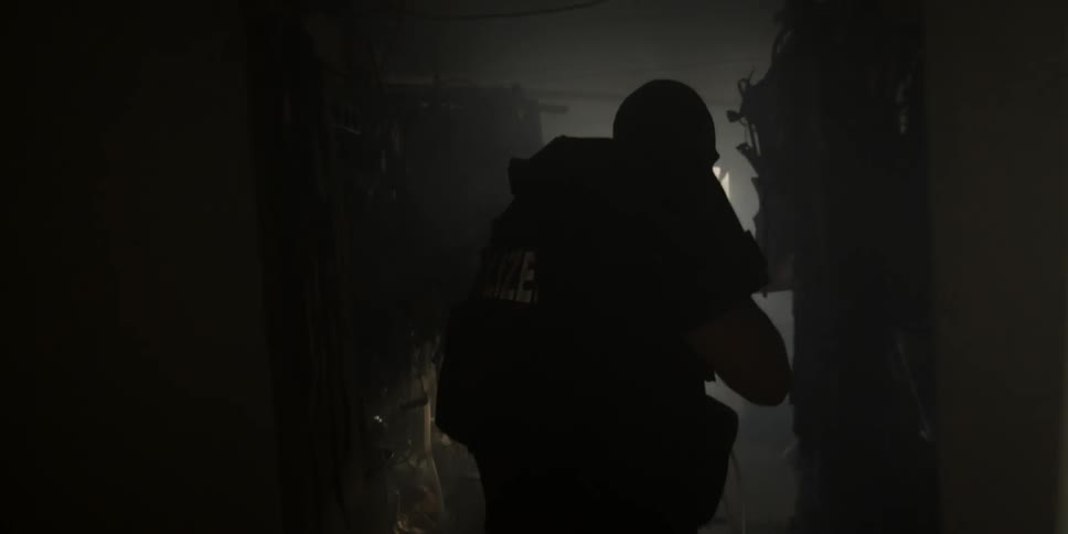 Police move through a dark hall with weapons